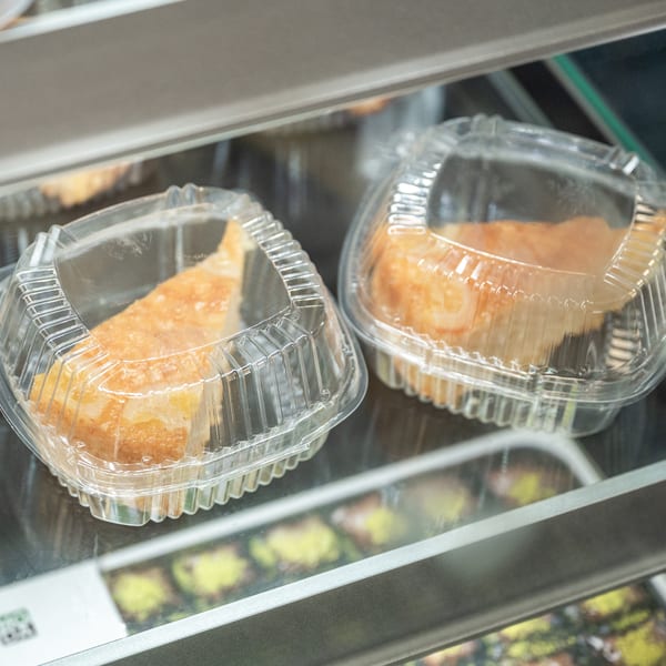 Two golden cake slices in clear plastic containers on a display shelf.